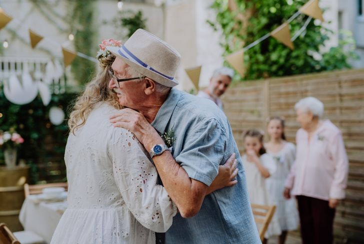 Mature bride receiving congratulations at wedding reception outside in the backyard.
