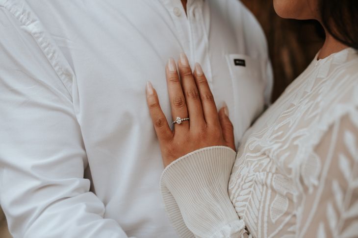 Close-up of boho couple in nature holding hands and walking, hugging having fun for their engagement photo session.